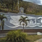 Chaguaramos jóvenes acompañan el mural de entrada de San Antonio de Capayacuar. Patrimonio cultural del estado Monagas, Venezuela.